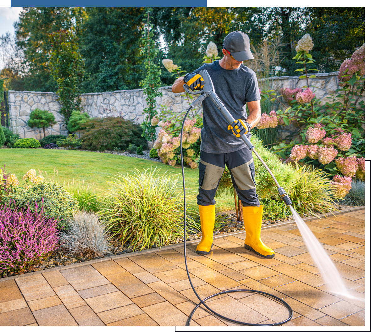 Man power washing patio in garden