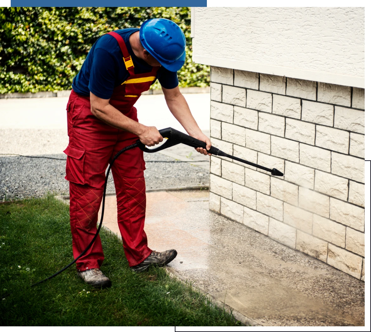 Person using pressure washer on stone wall